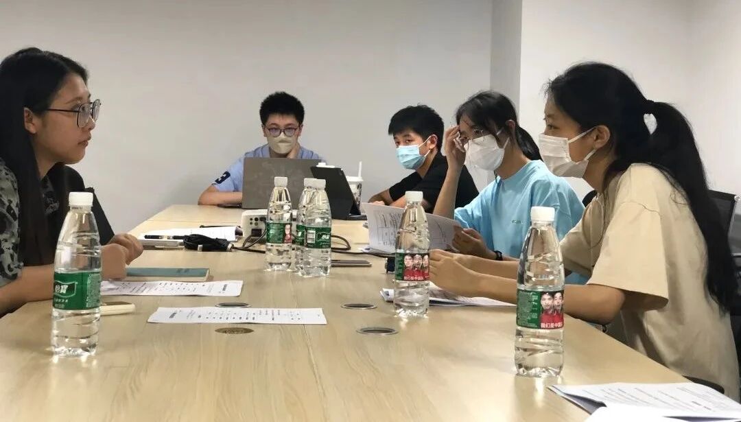 Team members in masks meeting around a conference table with an organization during a site visit
