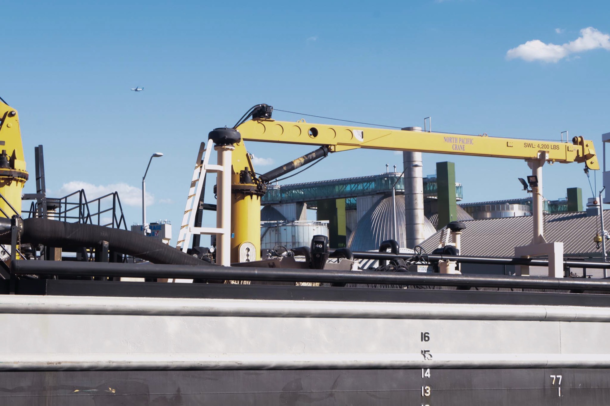 A yellow crane working on a barge on Newtown Creek