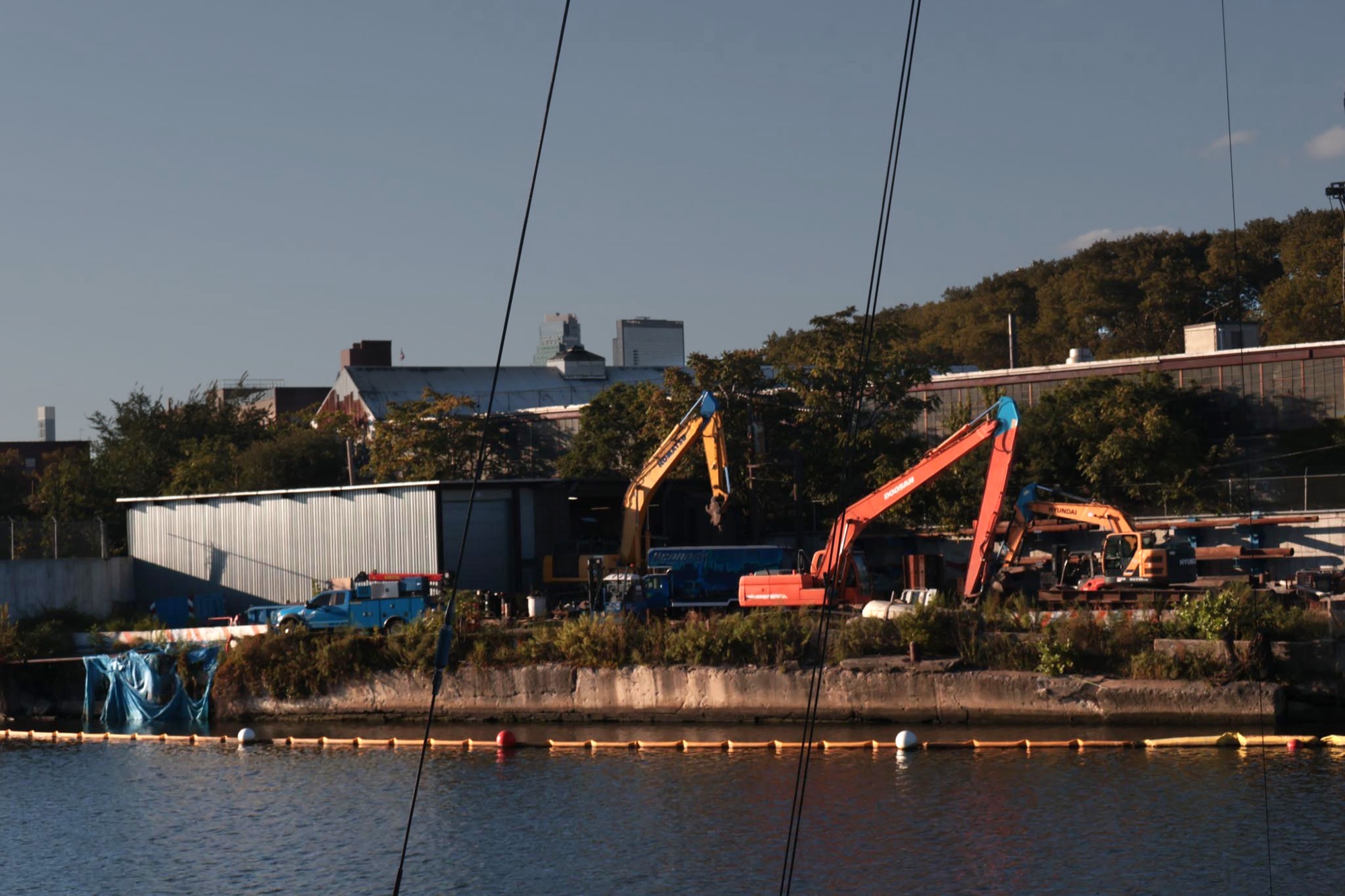 Excavators working along the shoreline of Newtown Creek at dusk