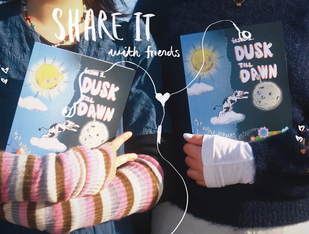 Two people holding printed copies of Dusk Till Dawn, with a hand-drawn 'Share it with friends' doodle connecting the two covers by a heart